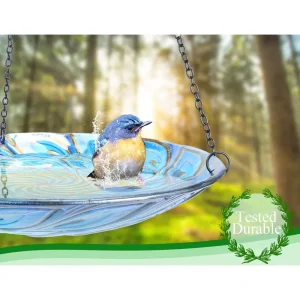 A small bird enjoying a refreshing bath in a glass hanging bird bath, water splashing around it